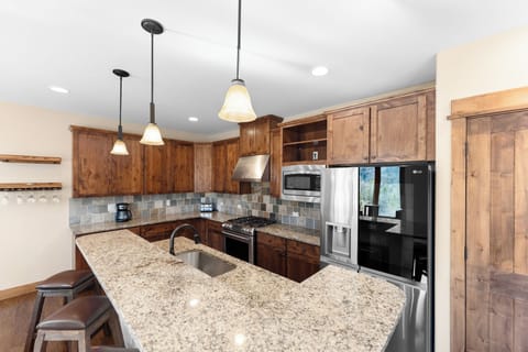 Full size kitchen with granite countertops, high end stainless steel appliances, and breakfast bar for additional seating