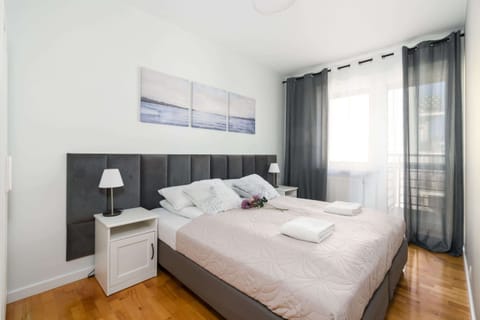 A bright and elegant bedroom with a large bed, soft bedding, and modern wall art, creating a relaxing space.
