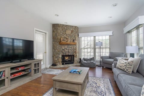 Cozy living room with stone fireplace, couch, games, and TV.
