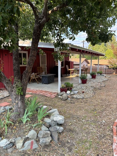 Relax on the shaded patio surrounded by trees, garden beds, and the calming feel of nature.