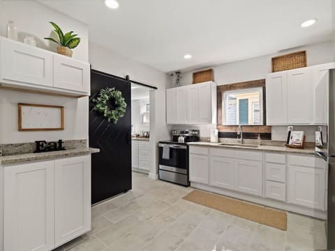 Fully equipped kitchen with stainless steel appliances   - White cabinetry and modern finishes with barn door style   - Bright space ready for home-cooked meals