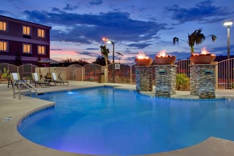 Outdoor pool deck with fire features and lounge chairs.