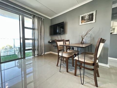 Open lounge with four seater couch + dinner table + four chairs + flat TV