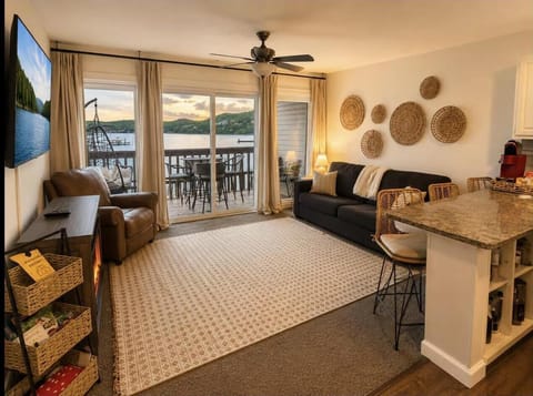 Living room features sliding glass doors opening to a balcony with lake views, a armchair, and a sleeper sofa.