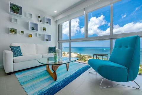 Settle into your bright living room where floor-to-ceiling windows frame stunning ocean views. The modern décor and coastal colors invite you to unwind after a day at the beach.