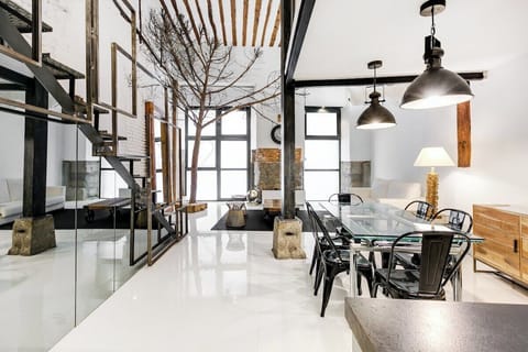 General view of the dining room  seen from the kitchen area. There is a dining table for six people and 
in the background, the entrance door and the living room area with a sofa bed.