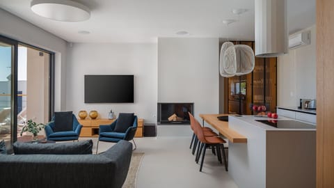 Couch and armchairs in the spacious living room with a fireplace and access to the terrace, and a modern kitchen with kitchen island