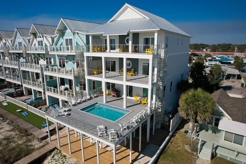 Modern beachfront rental with private pool, multiple decks, and bright yellow accents in a coastal community.
