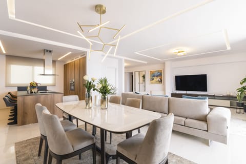 The modern open-plan living space includes a dining area and a Smart TV.