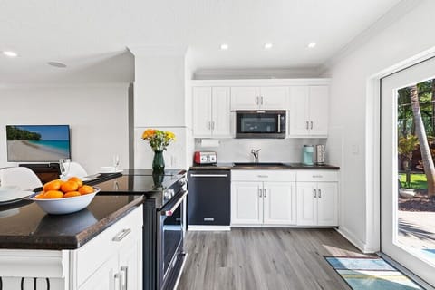 PREPARE A FAMILY MEAL IN THE FULLY-EQUIPPED KITCHEN FEATURING A KEURIG COFFEE MACHINE, UPDATED APPLIANCES AND BAR SEATING WITH POOL VIEWS