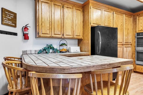 Kitchen: Drip coffee maker, small fireplace, cooking utensils, tableware, bar seating for 4