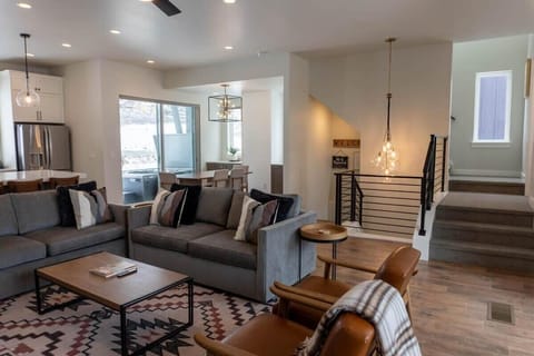 The living room is set up with everything you need for a relaxing space with an electrical fireplace, 65” smart TV, two sofas and two chairs, and well-placed decor creating a cozy home ambiance.