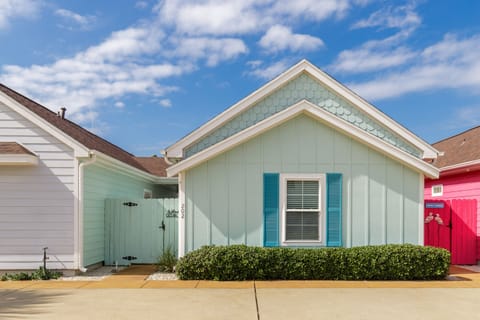 Charming coastal cottage with distinctive seafoam green siding and turquoise shutters creates a welcoming beachside retreat.