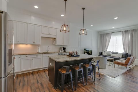 The open kitchen with white cabinetry, a marble island, and pendant lighting is perfect for entertaining.