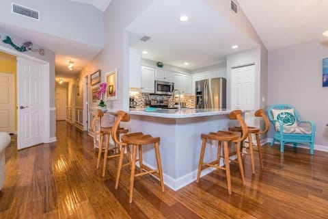 Modern kitchen with breakfast bar seating and hardwood floors.