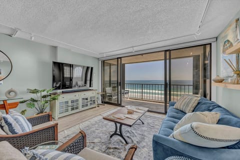 Step into your coastal living room where plush seating faces stunning ocean views through floor-to-ceiling glass doors. Your private balcony awaits with the sound of waves just beyond.