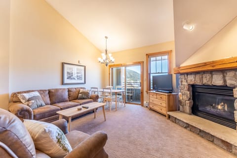 Cozy up by your crackling stone fireplace while mountain views frame your peaceful living space through floor-to-ceiling windows.