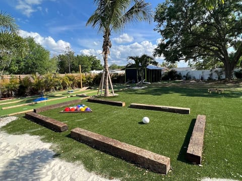 Private backyard mini golf course with palm trees, colorful balls, wooden obstacles and lush green turf, Orlando Florida
