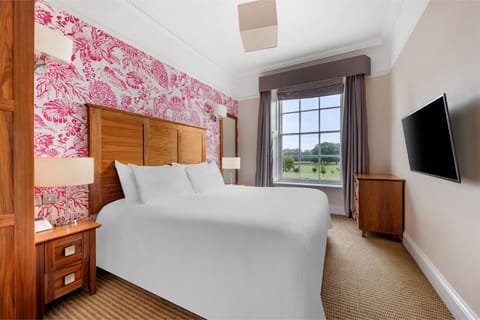 A cozy bedroom space with a welcoming bed and vibrant accent wall.