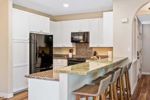 Full kitchen with breakfast bar, granite counters, and modern appliances