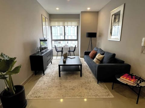 
Enter the living room flooded with natural light, featuring a comfortable couch, a TV, and a coffee table. By the window, a small table awaits for dining or work, accommodating two. Enjoy the serene atmosphere and scenic view.
