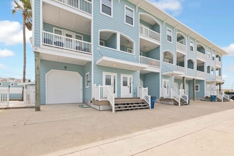 Coastal vacation rental building featuring multiple balconies and beach-style architecture under bright blue skies with palm trees nearby.