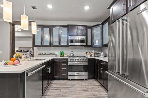 Fully equipped kitchen space features stainless steel Viking appliances, stone countertops, and bar seating for four