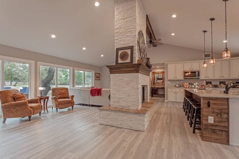 Grand room with floor-to-ceiling fireplace centerpiece, multiple sitting areas, an open kitchen and dining room.