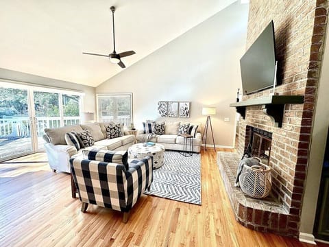 Open living room with ample seating, a fireplace, and a flat-screen television.