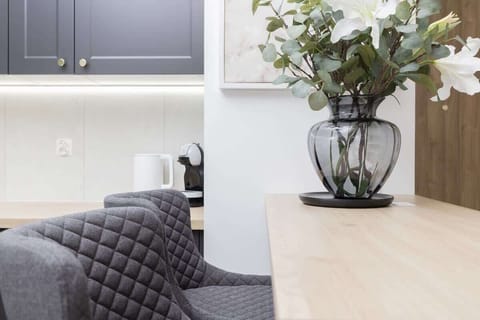 Dining area with gray chairs, floral centerpiece, and light cabinetry.
