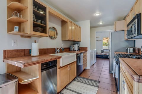 Other side of kitchen with dishwasher, large sink, trash compactor, and stocked with plenty of cookware and dinnerware.