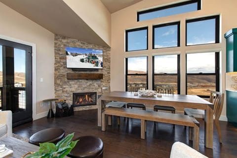Mayflower Lakeside 1121-304: The open concept living and dining area features a rustic wood table by stone fireplace, perfect for cozy, modern dining.
