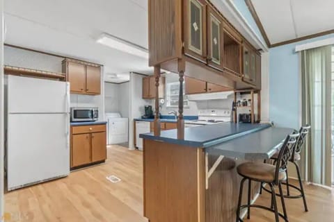 Laundry room with washer & dryer off open kitchen plan with barstool seating.