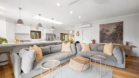 With its soothing neutral tones of elegant white walls, cosy grey couches, and accents of soft orange pillows, the living room is as welcoming and calming as it can be.