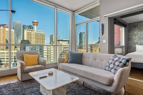 Living room with a Smart TV, cozy seating options and epic views of the iconic Calgary tower.