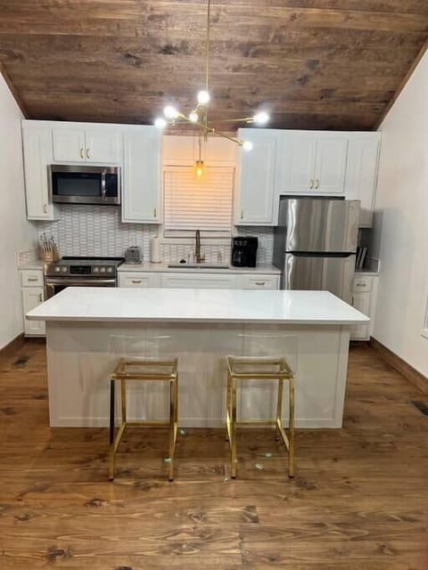 Your kitchen has quartz countertops and island, stainless steel appliances, and gold accent pieces. 