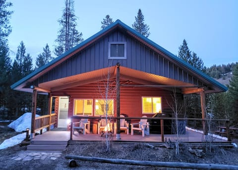 Embrace the enchanting twilight ambiance as Valley Creek Cabin's covered patio beckons with a cozy fire pit and convenient gas BBQ, perfect for evening gatherings.