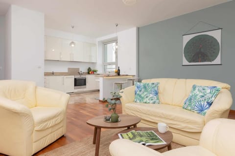 A bright and welcoming living area with a soft beige sofa, a glass coffee table, and decorative artwork.
