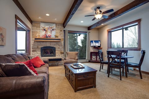 Cozy up by your stone fireplace while enjoying mountain views from this warm living space with rustic beams and comfortable seating.