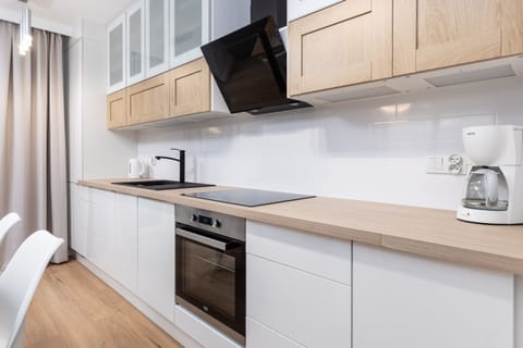 A modern kitchen with white cabinets, wooden countertops, and integrated appliances, designed for convenience and style.
