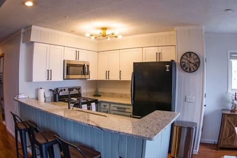 New granite countertops with room for four barstools around overhanging bar top. Oversized deep sink with spray capable faucet and garbage disposal.