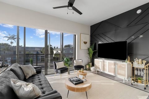 [Living Room] - wraparound balcony w/ views, black leather couch, velvet accent chairs, 65" TV w/ complimentary Netflix, board games, bar cart, blanket, custom accent wall