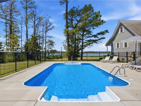 Private pool overlooking tranquil waterfront views, surrounded by shaded seating areas and mature trees for your perfect sunny afternoon retreat.