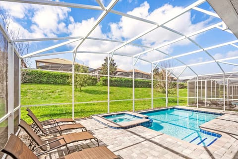 Relax in your private screened-in pool and hot tub, surrounded by lush greenery and ample lounge seating for ultimate comfort.