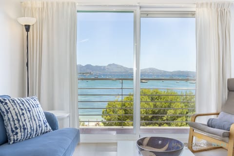 From the living room of this bright apartment, enjoy stunning views over the Bay of Pollença. The large glass doors connect the interior with nature, allowing you to admire the sea, boats, and mountains from the comfort of the sofa.