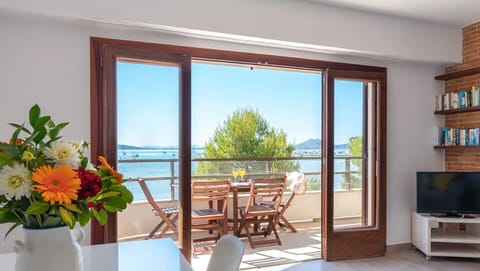 Bright living-dining room with access to a furnished terrace and beautiful sea and bay views from our holiday apartment in Mallorca.