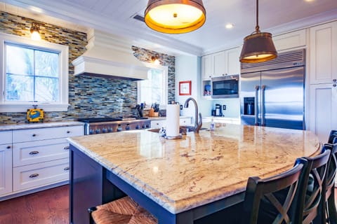 The kitchen features stainless steel appliances, including a range, built-in refrigerator and two dishwashers.