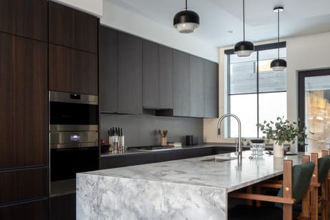 Step into your chef's paradise with sleek dark cabinetry, gleaming marble countertops, and professional-grade appliances that make cooking feel effortless and inspiring.