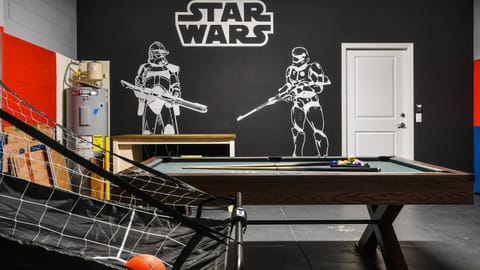 Star Wars-themed game room with a pool table, basketball arcade, and striking wall art. Fun for all!