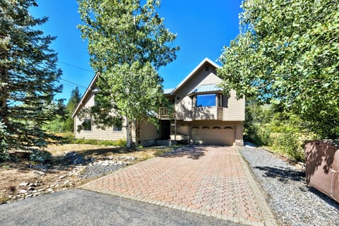 A charming mountain home with warm wood siding and thoughtful design nestled among towering trees on a peaceful residential street.